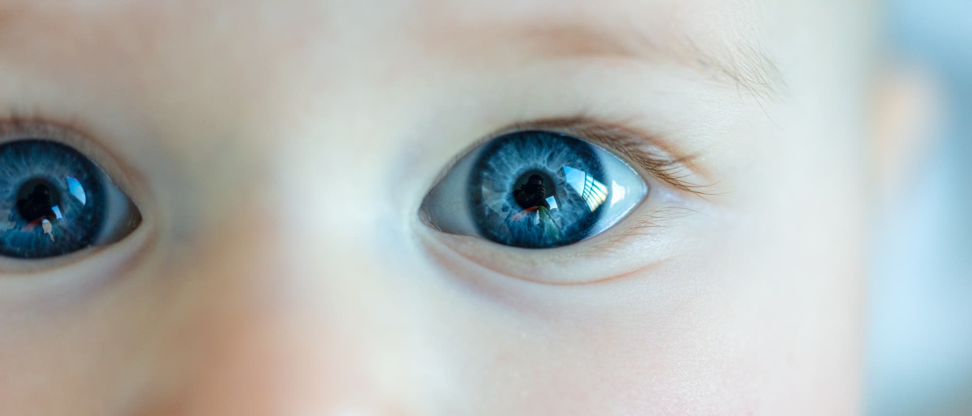 Nahaufnahme eines Babys mit großen, leuchtend blauen Augen, die direkt in die Kamera blicken. Das Bild zeigt die Details der Iris und die Reflexionen im Auge. Der Hintergrund ist unscharf, wodurch der Fokus auf dem Gesichtsausdruck des Babys liegt. Nahaufnahme eines Babys mit großen, leuchtend blauen Augen, die direkt in die Kamera blicken. Das Bild zeigt die Details der Iris und die Reflexionen im Auge. Der Hintergrund ist unscharf, wodurch der Fokus auf dem Gesichtsausdruck des Babys liegt.