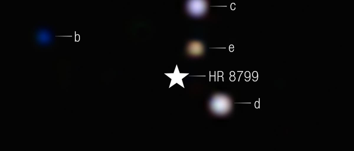 Ein Bild des Sternsystems HR 8799, das im Zentrum als weißer Stern dargestellt ist. Um den Stern herum sind vier Exoplaneten mit den Bezeichnungen b, c, d und e sichtbar. Planet b erscheint blau und ist links vom Stern positioniert. Die Planeten c, d und e sind rechts vom Stern und erscheinen in verschiedenen Farbtönen. Der Hintergrund ist schwarz. Ein Bild des Sternsystems HR 8799, das im Zentrum als weißer Stern dargestellt ist. Um den Stern herum sind vier Exoplaneten mit den Bezeichnungen b, c, d und e sichtbar. Planet b erscheint blau und ist links vom Stern positioniert. Die Planeten c, d und e sind rechts vom Stern und erscheinen in verschiedenen Farbtönen. Der Hintergrund ist schwarz.