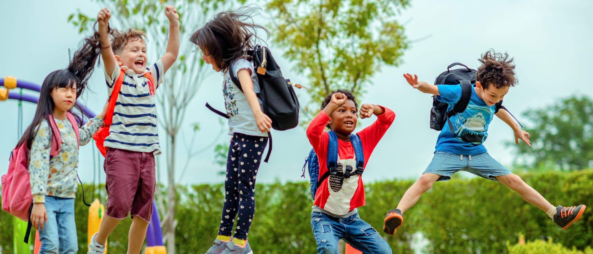 Mehrere Schulkinder beim Hüpfen auf einem Spielplatz.