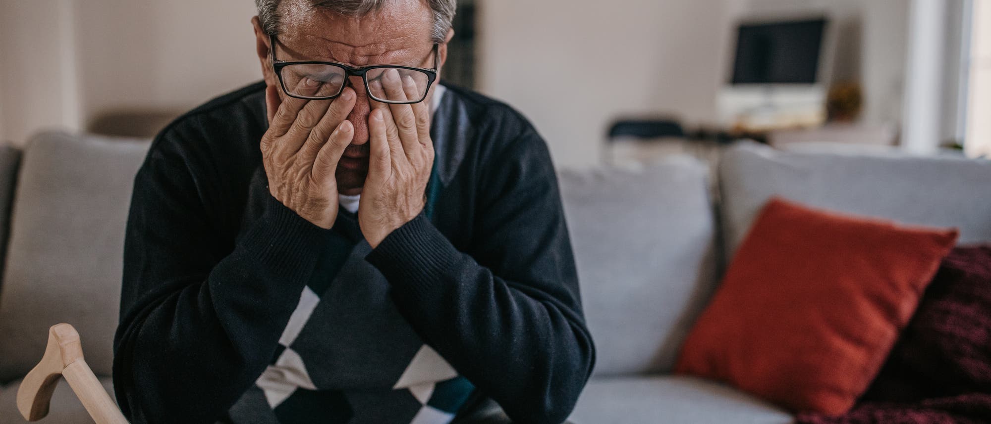 Älterer Mann sitzt auf Bett und reibt sich die Augen Älterer Mann sitzt auf Bett und reibt sich die Augen