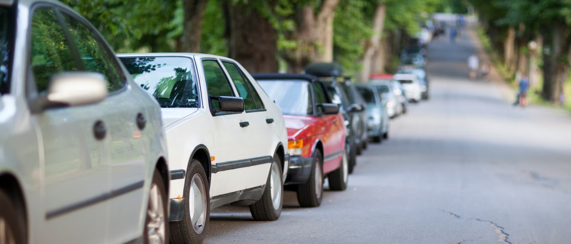 Eine Straße mit am Rand parkenden Autos. Eine Straße mit am Rand parkenden Autos.