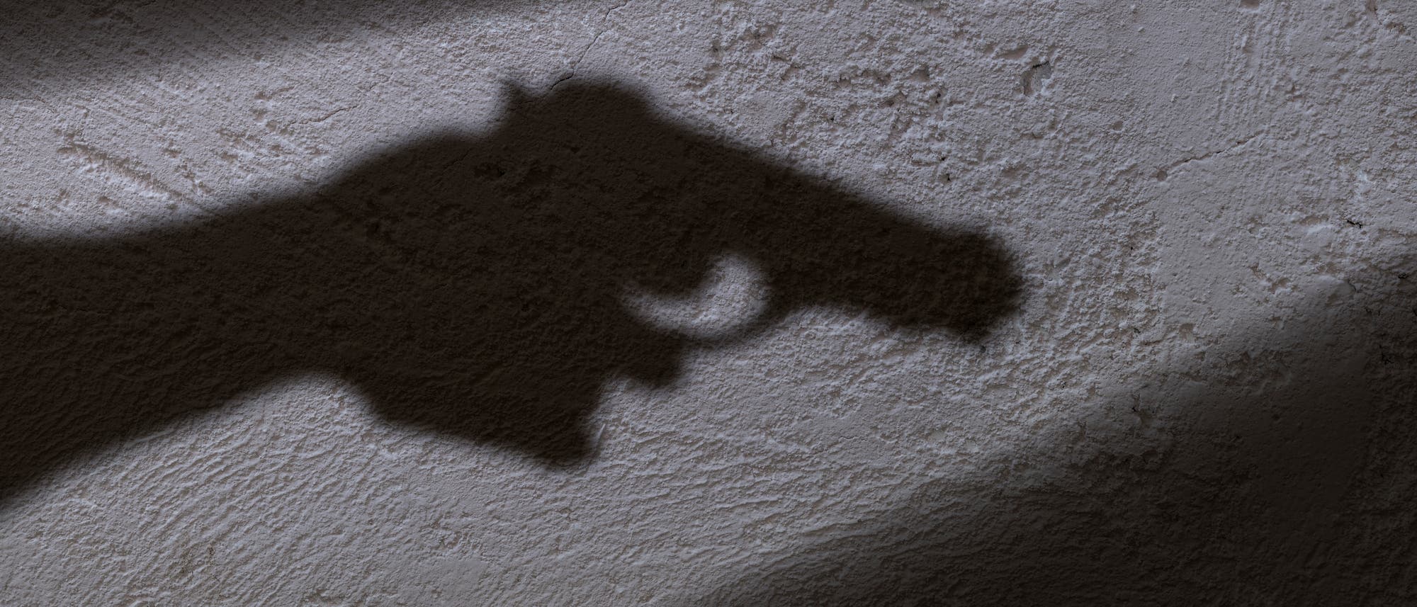 Schatten einer Pistole an der Wand Schatten einer Pistole an der Wand