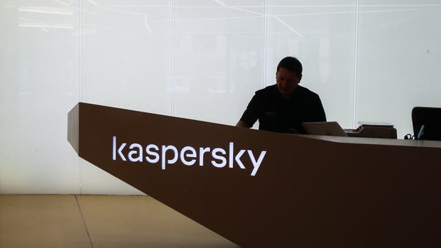 Ein Mann an einem dunklen Schreibtisch mit Kaspersky-Schriftzug.