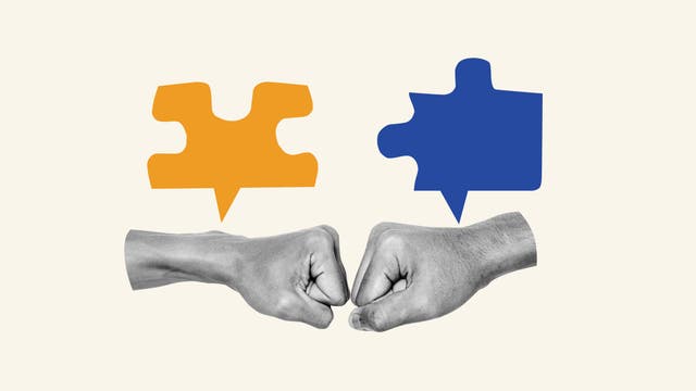 Zwei Fäuste stoßen sich an, symbolisierend für Zusammenarbeit oder Einigung. Über den Fäusten befinden sich zwei Sprechblasen in Form von Puzzleteilen, eines orange und das andere blau, die auf Kommunikation und Verbindung hinweisen. Der Hintergrund ist beige.