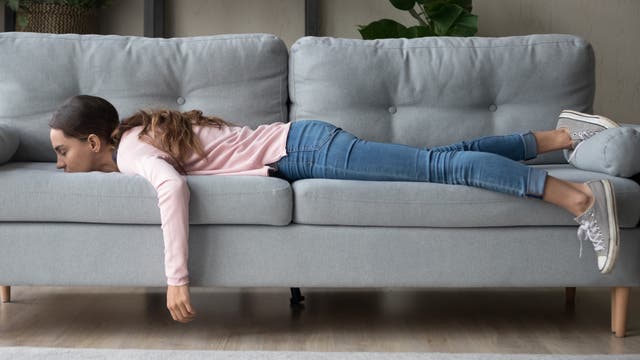 Junge Frau liegt bäuchlings auf dem Sofa und schläft