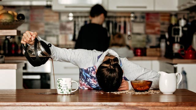 Müde Frau kippt ihren Kaffee neben die Tasse