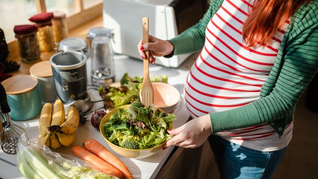 Schwangere bereitet sich einen Salat zu
