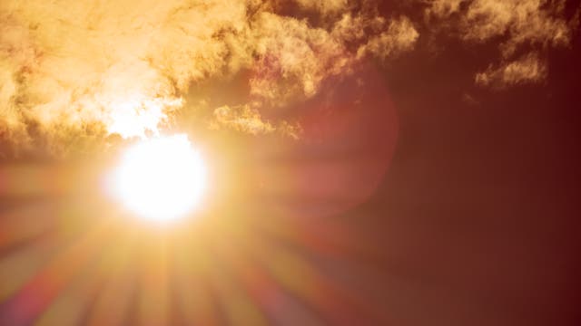 Die Sonne strahlt umgeben von leichten Schleierwolken