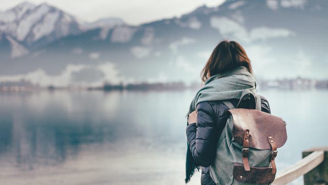 Frau blickt auf eine winterliche Seenlandschaft