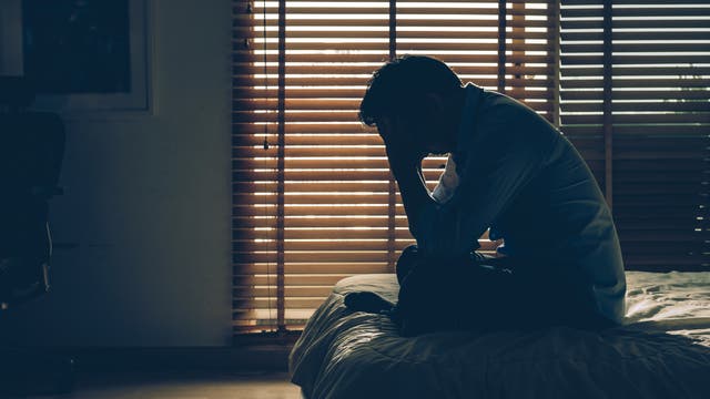 Mann mit Migräne in dunklem Zimmer