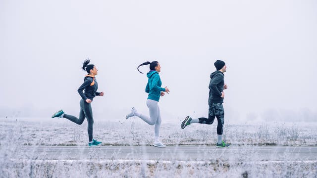 Drei junge Leute joggen in winterlicher Landschaft