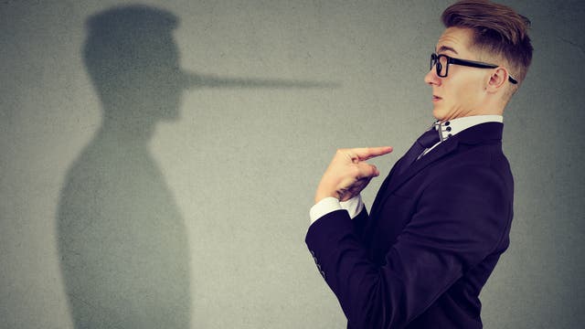 Ein Mann steht seinem Schatten gegenüber, zeigt auf sich selbst und wirkt verwundert, weil der Schatten eine lange Pinocchio-Nase hat.