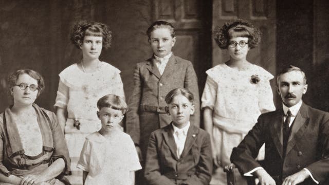 Historisches Schwarz-weiß-Foto einer Großfamilie. Rechts sitzt der Vater, links die Mutter. Dazwischen stehen und sitzen fünf Kinder verschiedenen Alters.